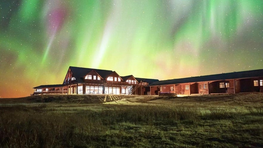 Hotel Ranga under vibrant northern lights, a cozy luxury stay near the Golden Circle with panoramic night skies.