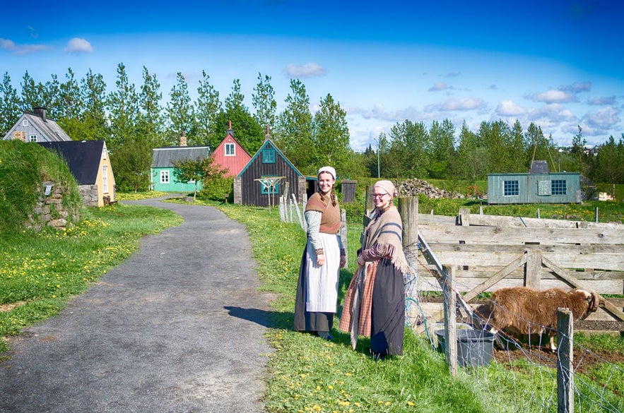 Häuser im Freilichtmuseum Arbaer, Mitarbeiter in traditioneller isländischer Kleidung, die sich um Nutztiere kümmern