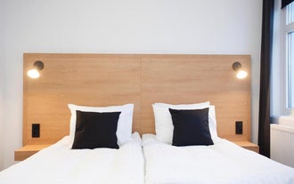 201酒店一间客房内,柔软的枕头整齐叠放在浅色木质床头板前。