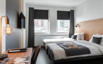 2 single beds are side by side next to a large window inside a hotel room at 201 Hotel