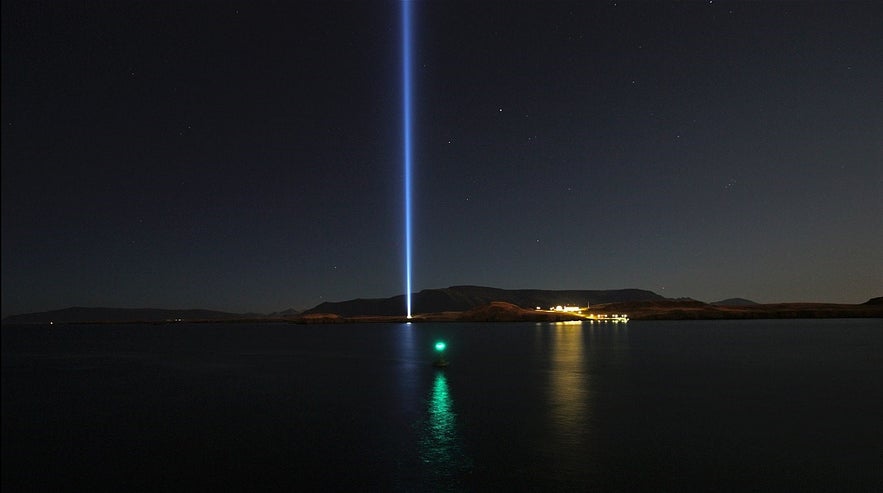 Wieża Imagine Peace Tower na wyspie Videy w Reykjaviku rozświetla rozgwieżdżone nocne niebo.