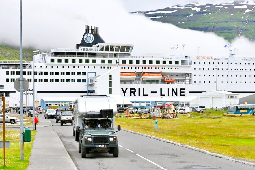 Cars and campervans driving off the Smyril Line Norrona ferry to Iceland in Seydisfjordur, East Iceland with mountains behind.