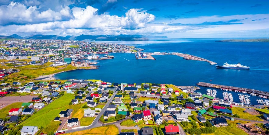 Aerial view of Torshavn in the Faroe Islands with the Smyril Line Norrona ferry to Iceland sailing offshore in the bay.
