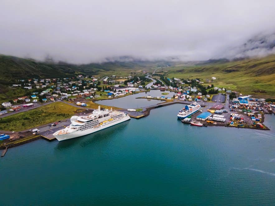 Aerial view of ships docked at Seydisfjordur Harbor with colorful houses and cloud-topped mountains
