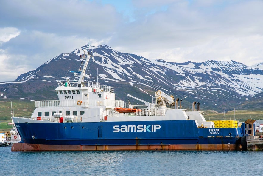 Saefari ferry to Iceland’s Grimsey Island docked in Dalvik Harbor with snow-capped mountains in North Iceland behind.