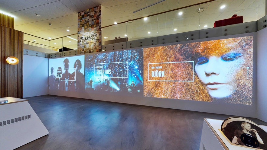 Interactive multimedia wall inside the Icelandic Museum of Rock 'n' Roll showcasing Björk, Sigur Rós, and Kaleo, with modern lighting and vinyl displays.
