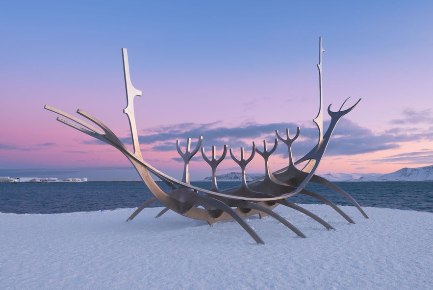 The Sun Voyager sculpture in Reykjavík, Iceland, captured at sunset in winter with snow on the ground and pastel skies over the Faxaflói Bay.