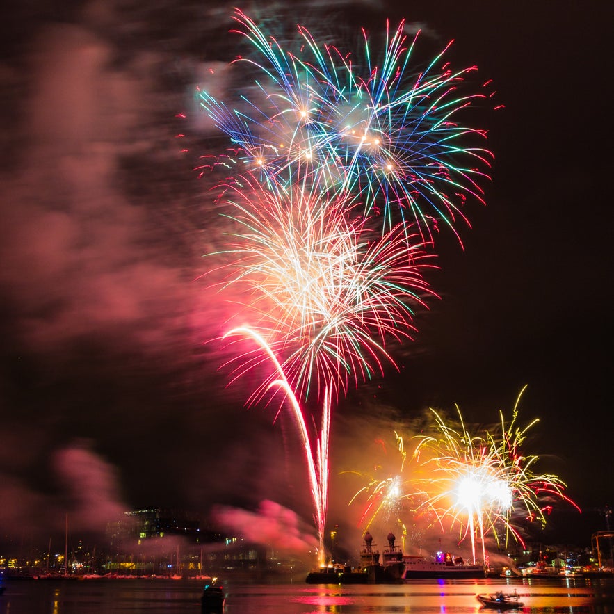 Vibrant New Year’s Eve fireworks over Reykjavík harbor in Iceland, lighting up the night sky with colorful bursts and reflections on the water