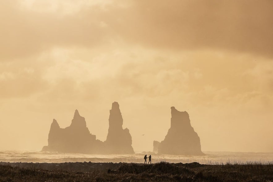 Reynisdrangar in Vik in Myrdal in the south of Iceland on a misty day with people walking along the black sand beach