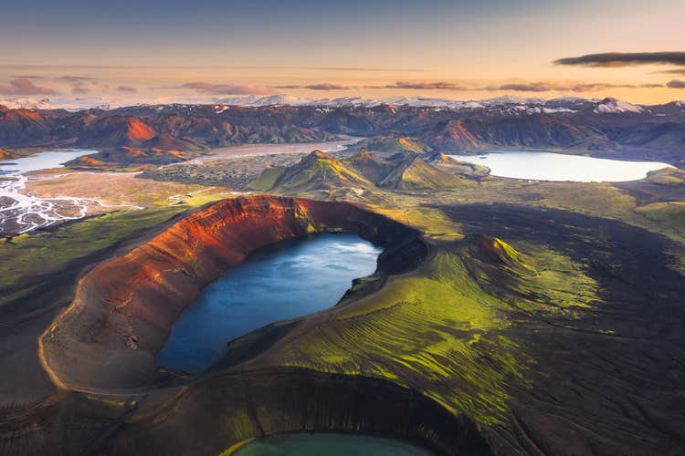 Hnausapollur crater lake in the Icelandic Highlands, with vivid blue water contrasting against red volcanic slopes in summer.