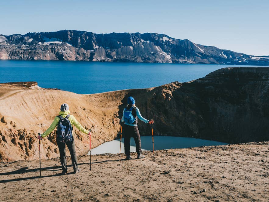 徒步者在阿斯基亚火山附近的地热火山口湖边，展现冰岛丰富的户外生活方式。