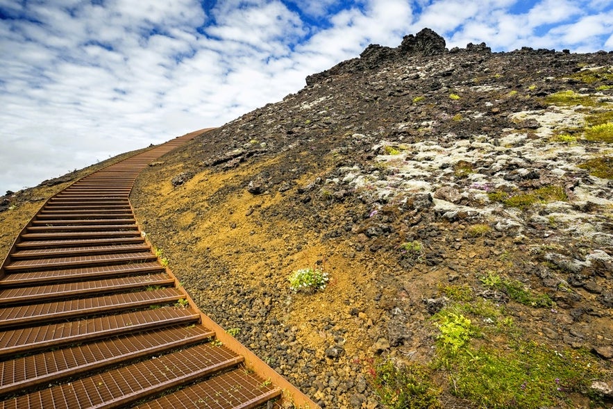 Metal staircase leading up Saxholl Crater in Snaefellsnes Peninsula, Iceland, offering panoramic views of volcanic landscapes.