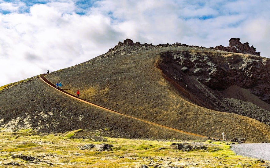Hiking up Saxholl Crater in Snaefellsnes Peninsula, Iceland, with scenic volcanic landscapes surrounding the Saxholl trail.