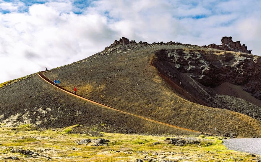 Hiking up Saxholl Crater in Snaefellsnes Peninsula, Iceland, with scenic volcanic landscapes surrounding the Saxholl trail.