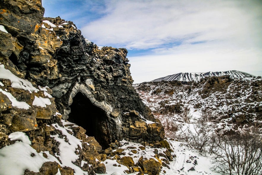 Winter view of Dimmuborgir in North Iceland, featuring a dark lava cave and snowy volcanic landscape near Lake Myvatn.