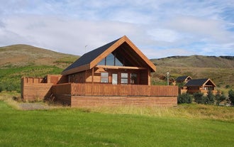 冰岛南部 Gljufurbustadir 度假屋的木质小屋外观,带露台,背靠群山。