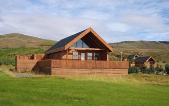 Wooden cabin exterior with a terrace and mountain backdrop at Gljufurbustadir Holiday Homes in South Iceland.