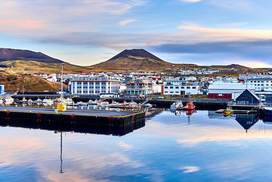 Harbor of Heimaey Island in the Westman Islands, with fishing boats and volcanic cliffs in the background.
