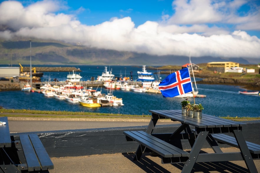 Flag of Iceland placed on a restaurant table with a harbor and ships in the background