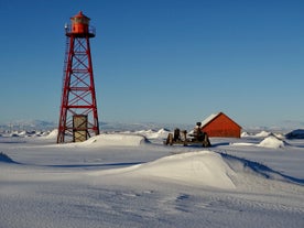 Witness the oldest steel lighthouse in Iceland, standing tall amidst a snowy landscape, on this enchanting ATV adventure.