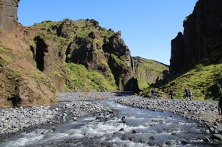 A glacial river flows over rocks between mountains in the Thorsmork Valley.