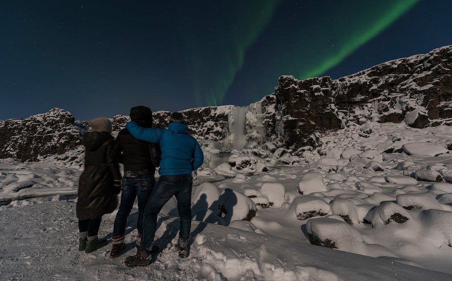 Group of travelers watching the northern lights in the sky at Thingvellir National Park