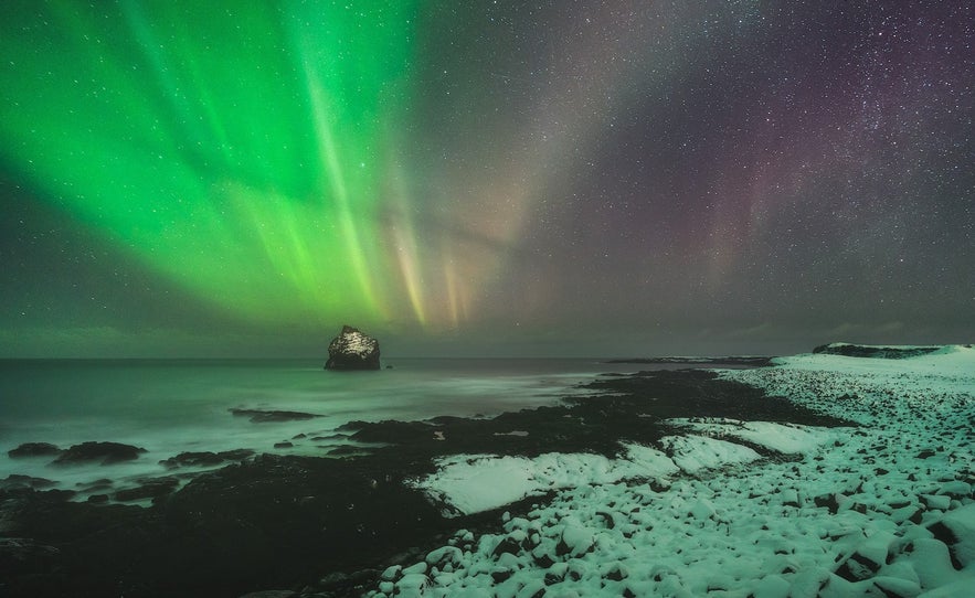 Northern lights over snowy and icy sea cliff on the Reykjanes Peninsula