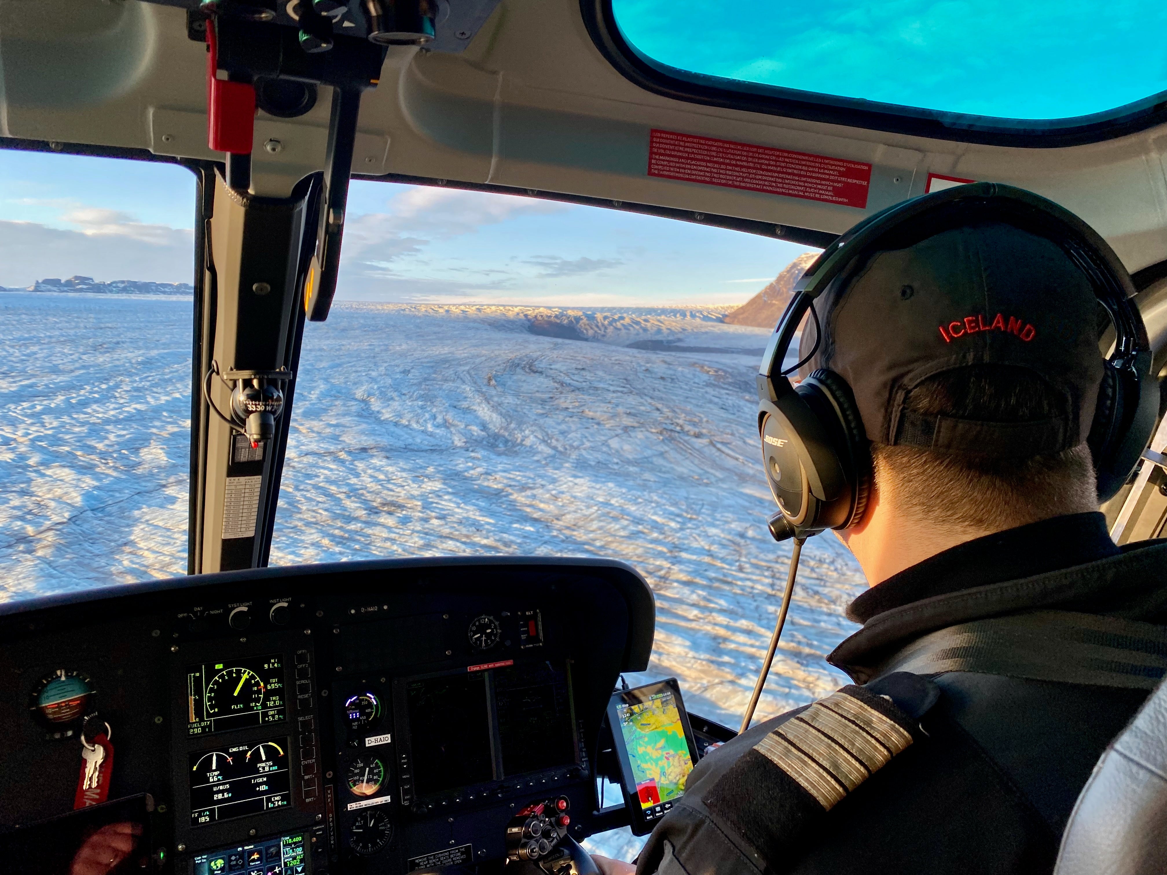 A helicopter pilot flies over an ice cap.