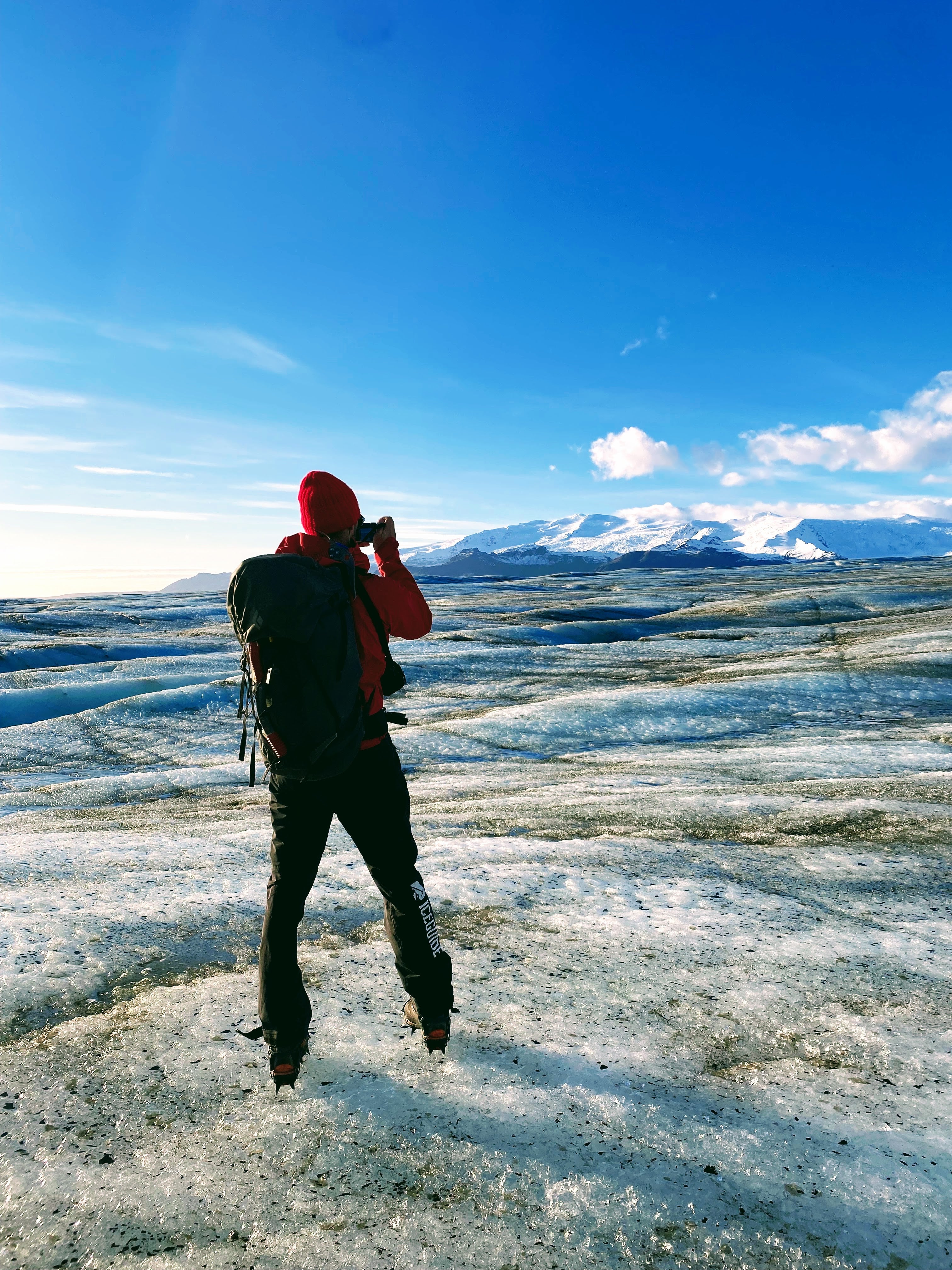 A traveler standing on a glacier takes a photo of the ice cap.