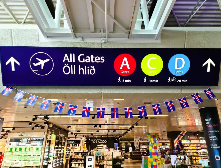 Borden op Keflavik Airport die reizigers de weg wijzen naar gates en duty-free winkels met IJslandse sterke dranken voor vertrek.