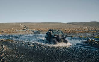 Kolumna buggy przeprawiająca się przez rzekę w okolicach Reykjavíku podczas pełnej adrenaliny, off-roadowej wycieczki.