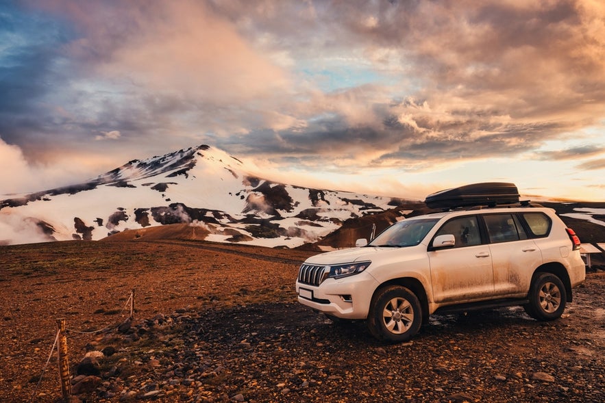 Un véhicule 4x4 garé à Kerlingarfjöll, avec des montagnes enneigées et de la vapeur s’échappant du terrain volcanique. Un véhicule 4x4 garé à Kerlingarfjöll, avec des montagnes enneigées et de la vapeur s’échappant du terrain volcanique.