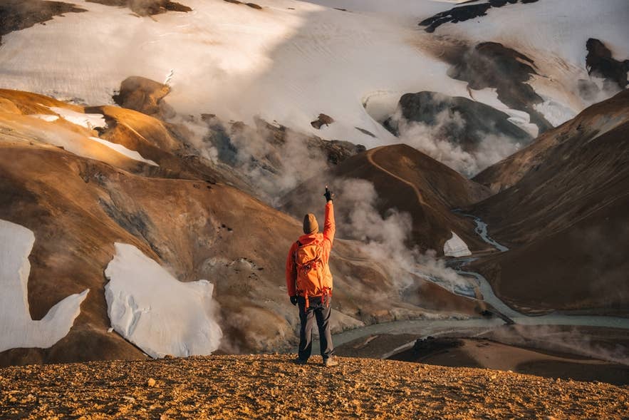Hiker standing in Kerlingarfjoll, surrounded by geothermal vents and volcanic mountains in Iceland's Highlands.