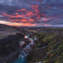Overhead view of a valley with a series of waterfalls on its cliff falling into the river below it.