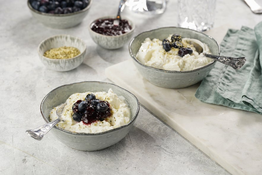 Two grey bowls with plain white icelandic dairy breakfast skyr with jam and fresh blueberries.