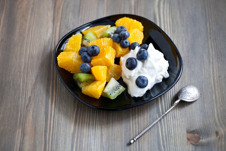 Fresh Icelandic skyr yogurt with berries and fruits on a black plate.