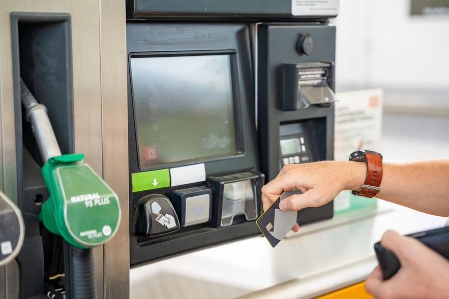 Close up view of a man paying for fuel with a card on terminal of self-service filling station.