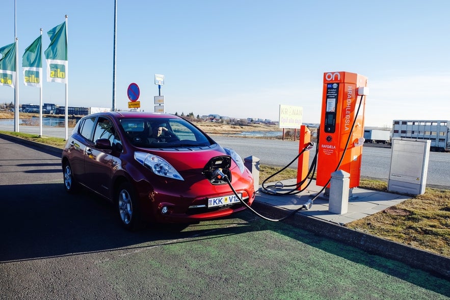 Red electric car charging at a station in Selfoss, Iceland.