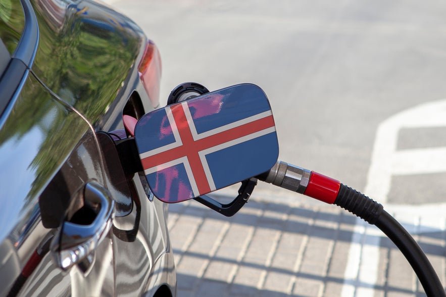 A car’s fuel tank flap features the Icelandic flag as it’s being refueled with a petrol pump at a gas station in Iceland.