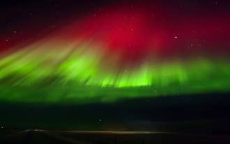 Ribbons fo green and red dance in a cool display of the northern lights near Seljalandsfoss Sky Reatreat in Hvolsvollur.