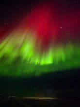 Groene en rode linten dansen in een prachtig schouwspel van het noorderlicht nabij Seljanlandsfoss Sky Retreat in Hvolsvöllur.