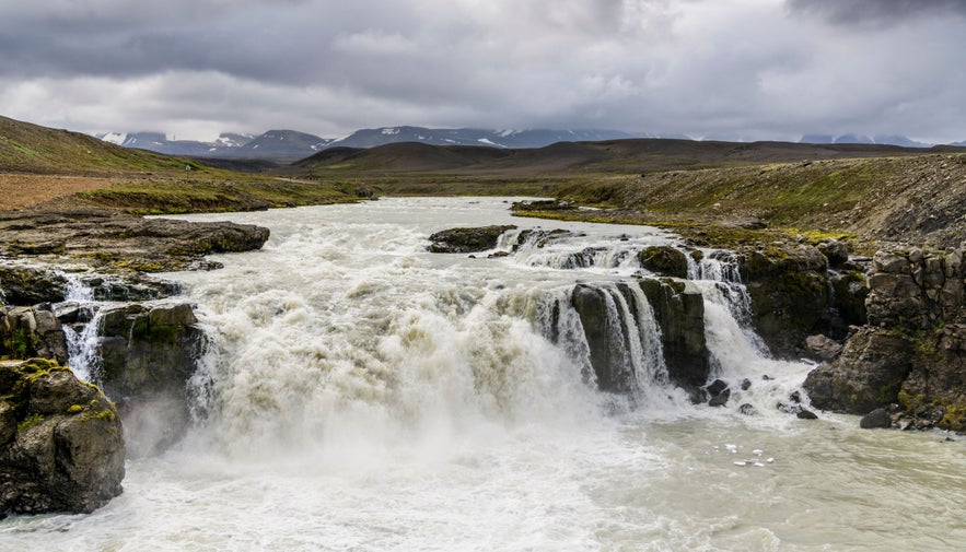 The Gygjarfoss Waterfall in Iceland, cascading over basalt cliffs, surrounded by rocky landscape.