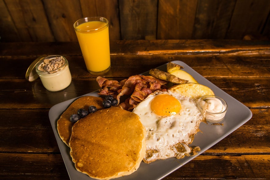 Hearty brunch with pancakes, eggs, bacon, and juice at Akureyri Backpackers café in North Iceland.