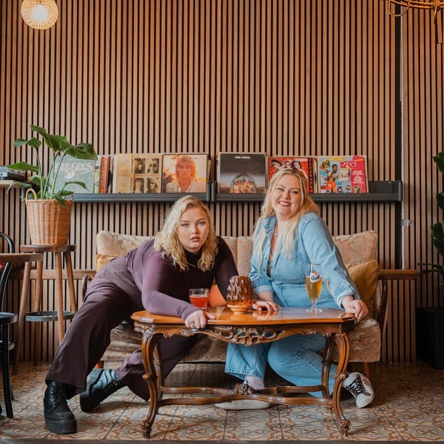 22 Bar’s business manager Magnea Fredriksen and entertainment director Margrétar Erla Maack pose on a couch with vinyl records in the background.