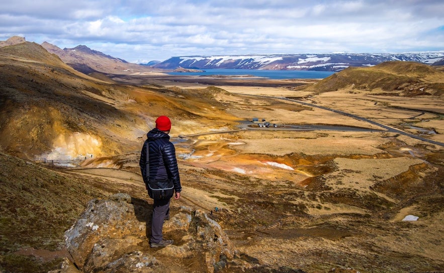 Man standin on a kliff overlooking Seltun geothermal area and Kleifarvatn lake