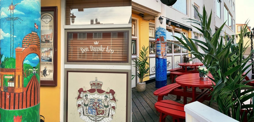 Outdoor patio of Den Danske Kro in Reykjavík with red benches, greenery, and painted columns.