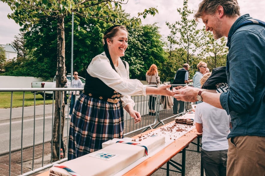 Woman giving out cake during the independence day of Iceland wearing the national costume of Iceland